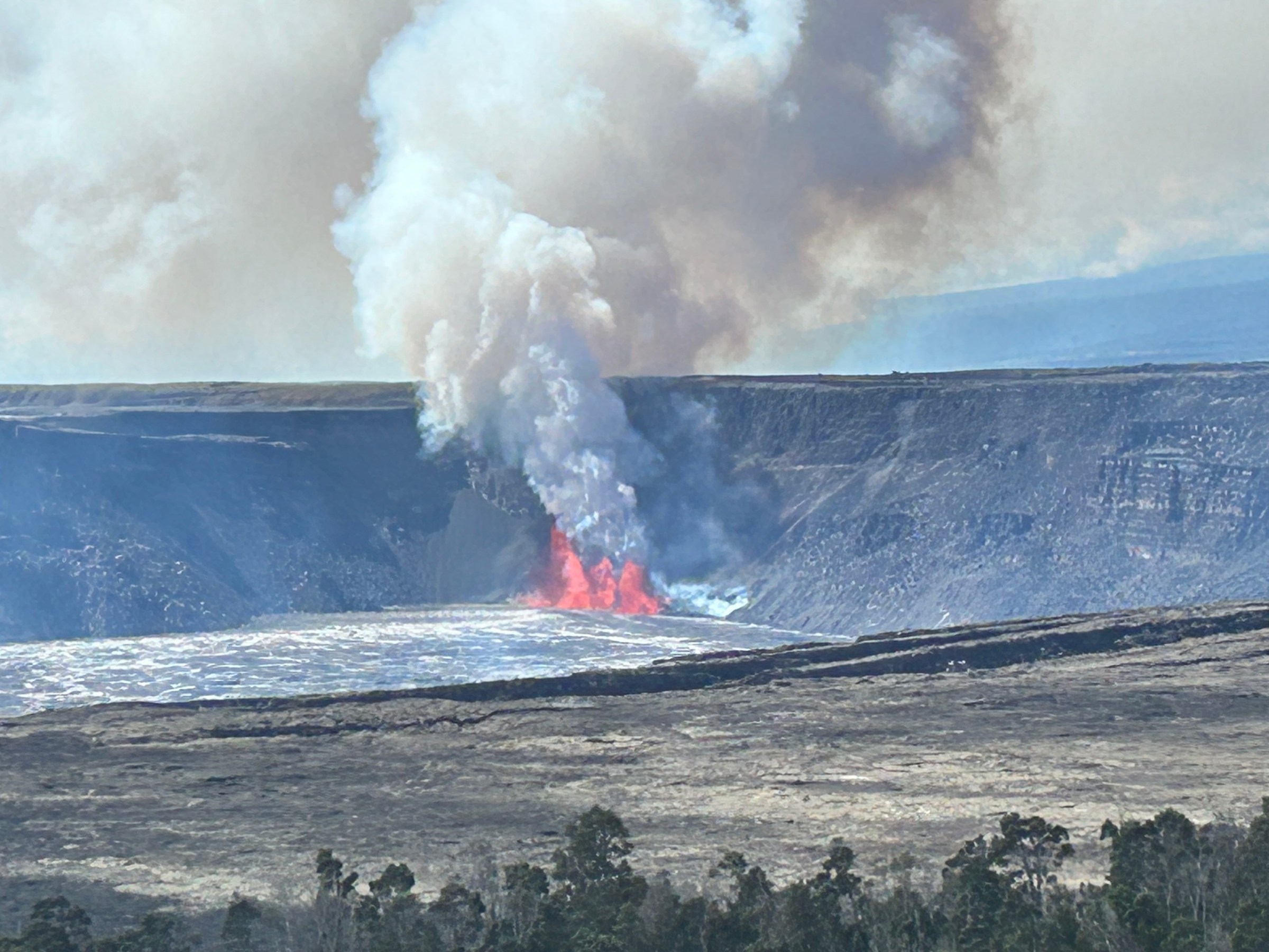 Volcanic eruption with smoke and lava flowing inside a crater.