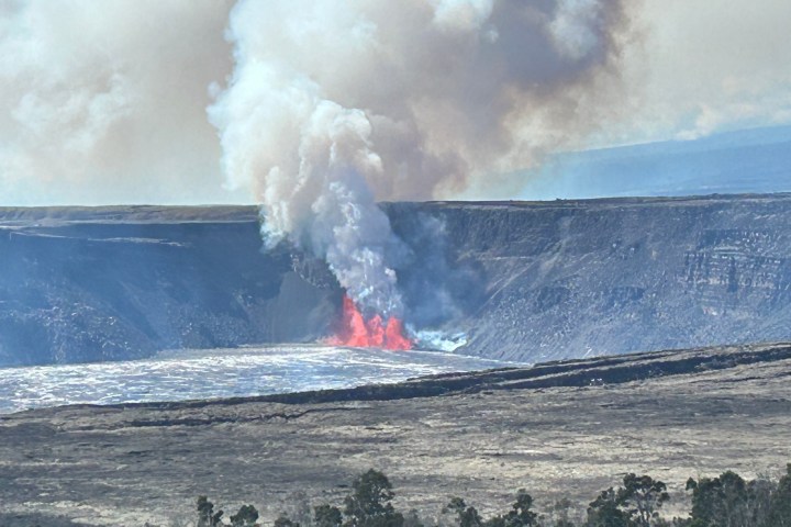 Volcanic eruption with smoke and lava flowing inside a crater.
